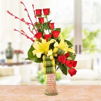 Floral Arrangement of 8 Red Roses, 2 Yellow Asiatic Lilies with dracaena leaves in a Glass Vase