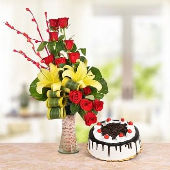 Floral Arrangement of 8 Red Roses, 2 Yellow Asiatic Lilies with dracaena leaves in a Glass Vase with Half Kg Black Forest Cake