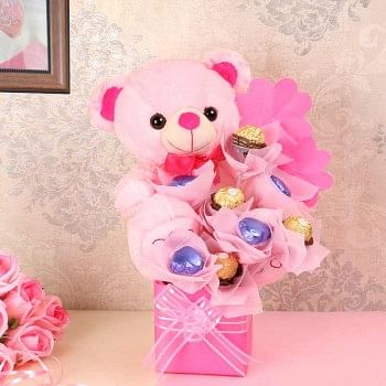 An arrangement of 1 Teddy Bear( 10 inches), 4 round-shaped assorted chocolates, 4 heart-shaped assorted chocolates in a vase